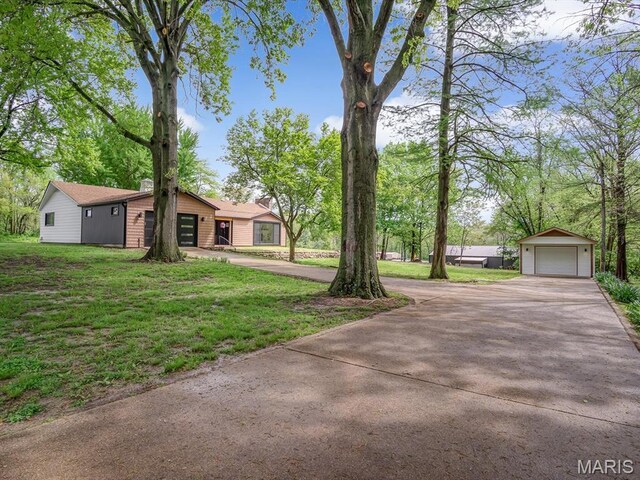 view of green lawn with concrete driveway, an outbuilding, and a detached garage