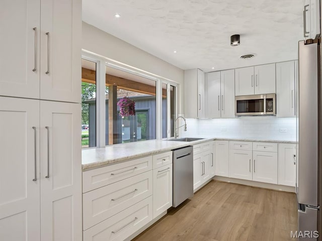 kitchen featuring a sink, appliances with stainless steel finishes, tasteful backsplash, white cabinets, and recessed lighting