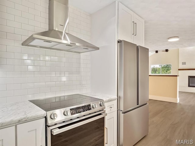 kitchen with stainless steel appliances, ventilation hood, tasteful backsplash, baseboards, and white cabinets