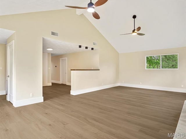 unfurnished living room with ceiling fan, high vaulted ceiling, baseboards, and wood finished floors