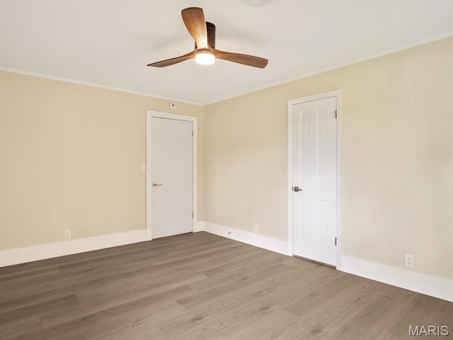 empty room with wood finished floors, ceiling fan, ornamental molding, and baseboards