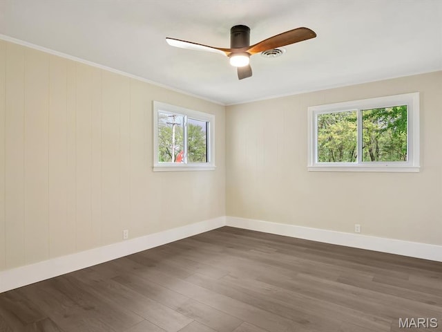 empty room with ceiling fan, wood finished floors, baseboards, and crown molding