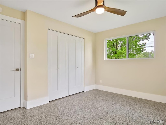 unfurnished bedroom featuring speckle patterned floor, baseboards, a closet, and ceiling fan