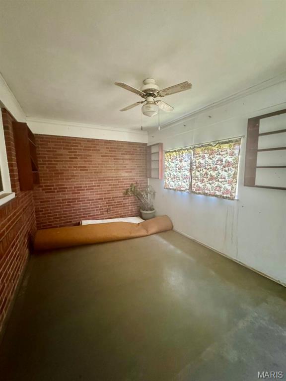1709 Korando Ave, Saint Louis, MO 63114 - spare room featuring brick wall, ceiling fan, finished concrete flooring, and crown molding