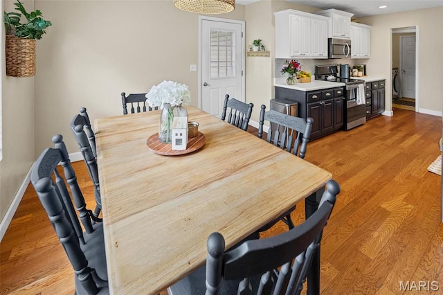 dining space featuring baseboards, light wood finished floors, and recessed lighting