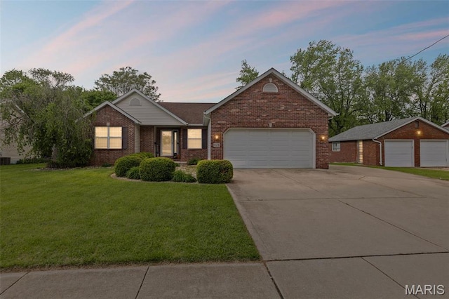 view of front of property with brick siding, a lawn, driveway, and a garage