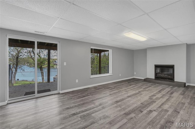 1211 Napoleon Dr, Bonne Terre, MO 63628 - unfurnished living room featuring a drop ceiling, baseboards, wood finished floors, and a glass covered fireplace