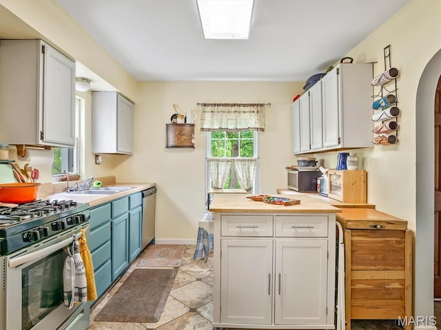 126 Sunset Ave, Collinsville, IL 62234 - kitchen with stainless steel appliances, a sink, arched walkways, baseboards, and blue cabinetry