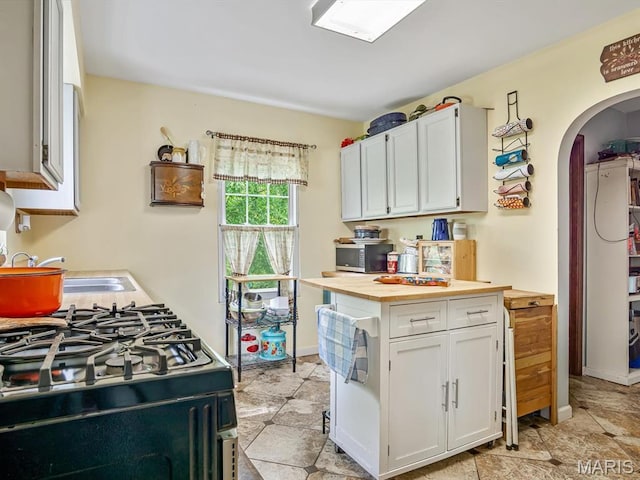 126 Sunset Ave, Collinsville, IL 62234 - kitchen with gas range oven, arched walkways, a sink, butcher block countertops, and white cabinetry