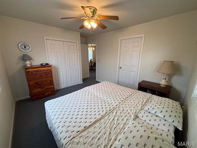 carpeted bedroom with baseboards, a closet, ceiling fan, and a chandelier