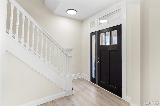 entryway with baseboards, wood finished floors, and stairs