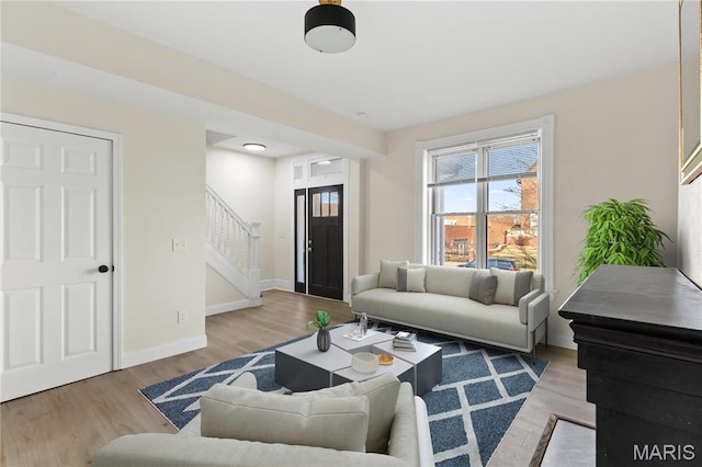 living room featuring stairs, baseboards, and wood finished floors
