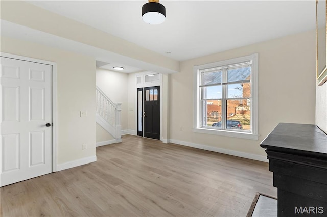 foyer featuring stairs, light wood finished floors, and baseboards
