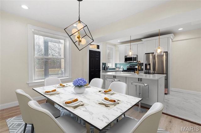 dining area with baseboards, recessed lighting, a chandelier, and light wood-style flooring