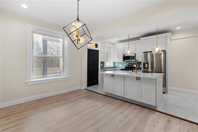 kitchen with appliances with stainless steel finishes, light countertops, a chandelier, baseboards, and recessed lighting