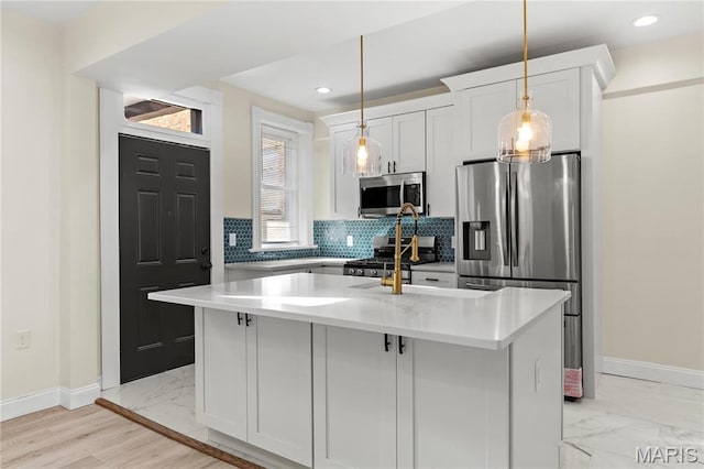 kitchen featuring appliances with stainless steel finishes, light marble finish floors, a kitchen island with sink, baseboards, and recessed lighting