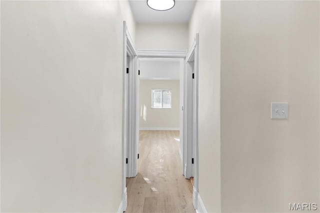 corridor with light wood-type flooring and baseboards