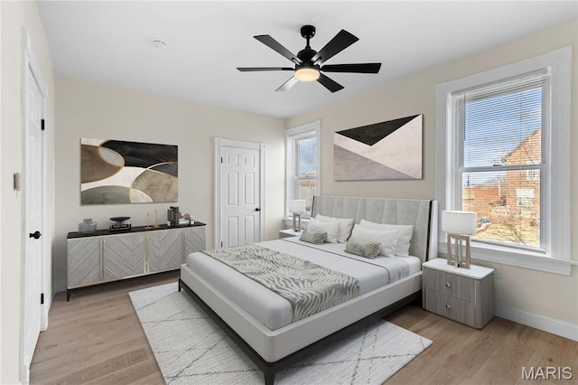 bedroom with light wood-style flooring, baseboards, and a ceiling fan