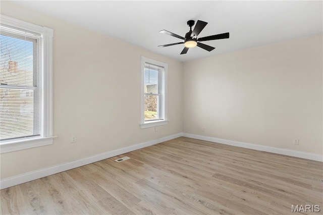 empty room featuring light wood finished floors, baseboards, and a ceiling fan