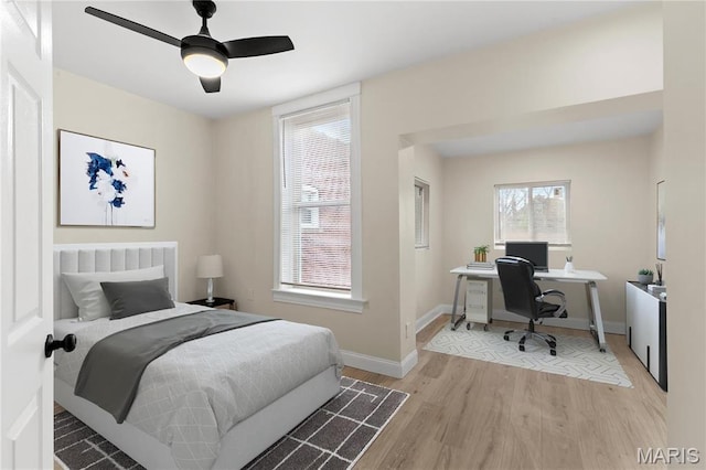 bedroom featuring wood finished floors, a desk, baseboards, and a ceiling fan