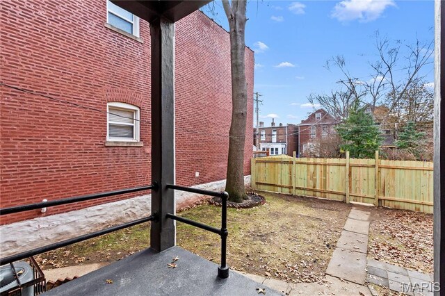 view of side of home featuring fence and brick siding