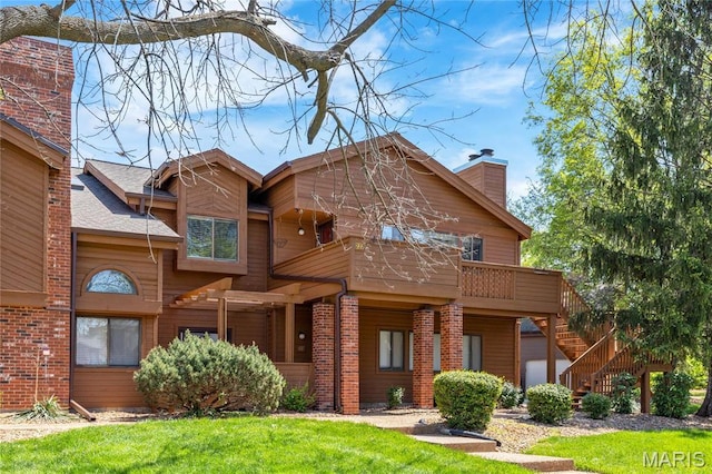 view of front of home featuring a front lawn, stairs, brick siding, and a chimney