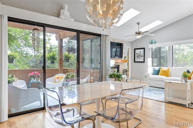 dining space with healthy amount of natural light, a skylight, vaulted ceiling, ceiling fan, and wood finished floors