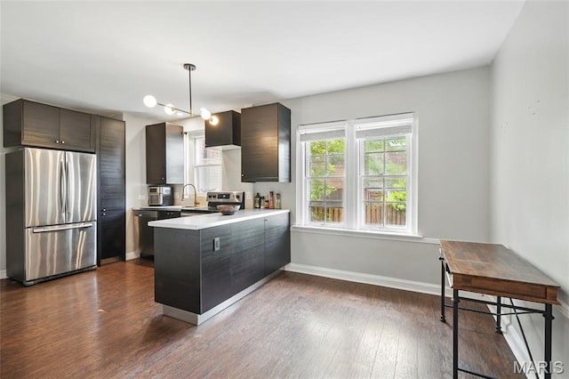 923 S Hanley Rd Unit A, Saint Louis, MO 63105 - kitchen featuring appliances with stainless steel finishes, a peninsula, light countertops, dark wood-type flooring, and baseboards