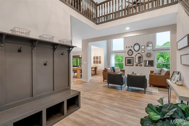 mudroom featuring a towering ceiling, light wood-style flooring, and baseboards