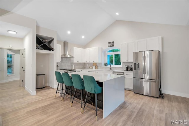 kitchen with stainless steel fridge with ice dispenser, wall chimney range hood, a kitchen island, a kitchen bar, and white cabinetry