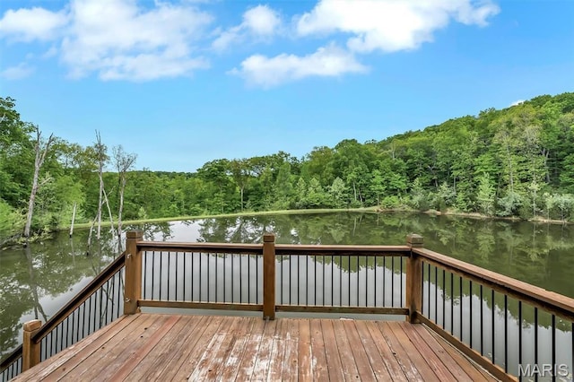 wooden terrace featuring a wooded view and a water view