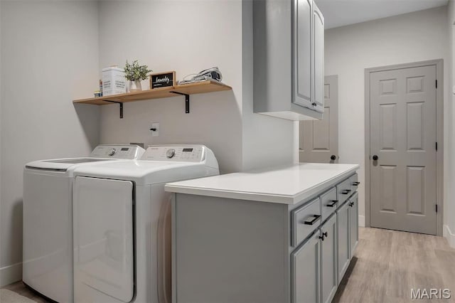 laundry area with independent washer and dryer, light wood-style floors, and cabinet space