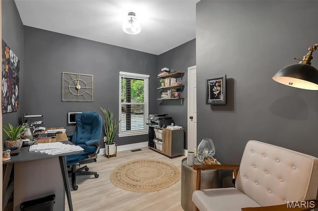 home office with light wood-style flooring and baseboards