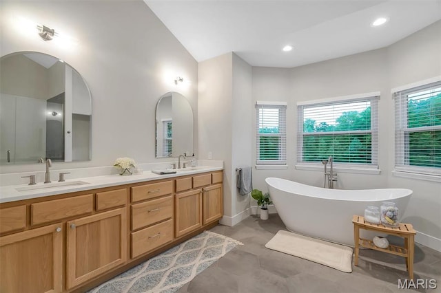 bathroom featuring a soaking tub, double vanity, baseboards, and recessed lighting