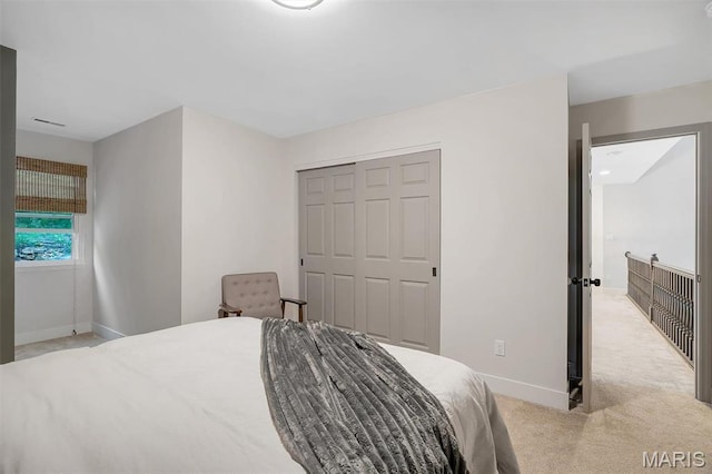 carpeted bedroom featuring baseboards and a closet