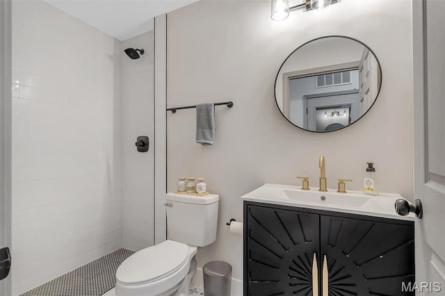 bathroom featuring toilet, a tile shower, and vanity