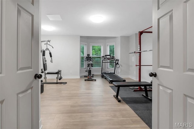 workout area featuring light wood-type flooring and baseboards