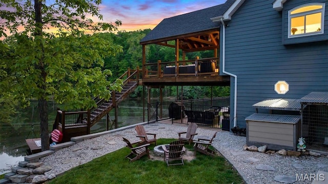 patio terrace at dusk with an outdoor fire pit, a deck with water view, and stairway
