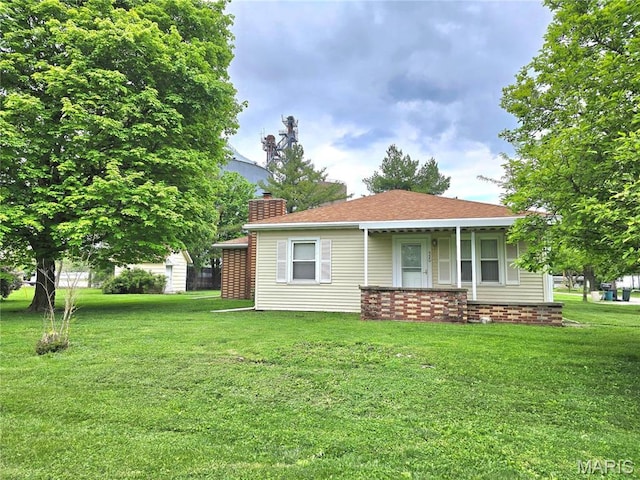 rear view of property with a lawn and a chimney