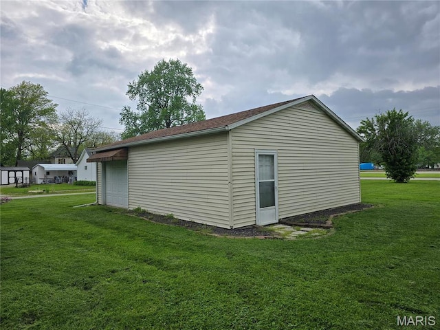 view of side of property featuring a lawn and a detached garage