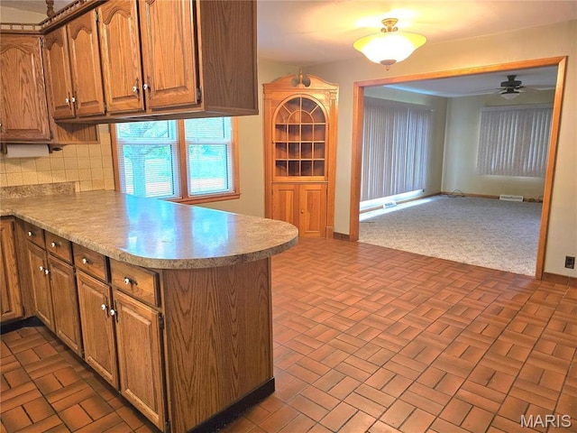 kitchen featuring a peninsula, open floor plan, decorative backsplash, and brick patterned flooring