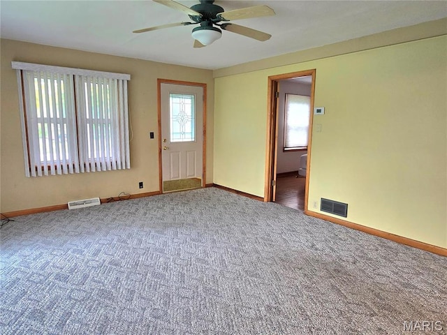 carpeted empty room with a ceiling fan and baseboards