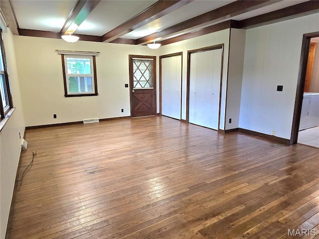 unfurnished room featuring beam ceiling, wood-type flooring, baseboards, and washer and clothes dryer