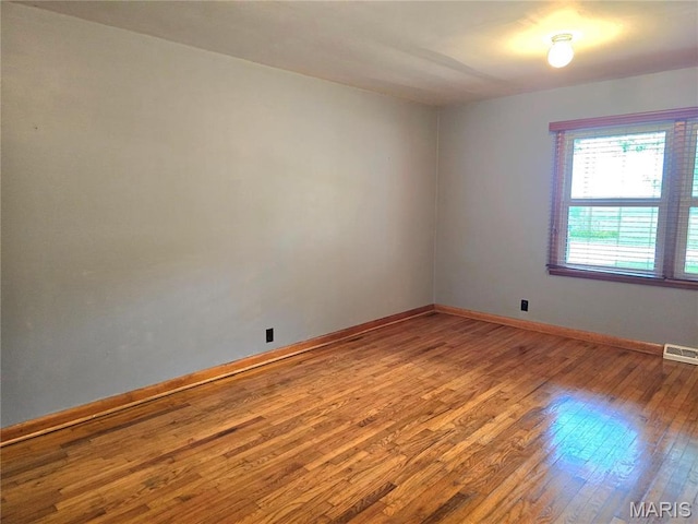 spare room featuring wood-type flooring and baseboards