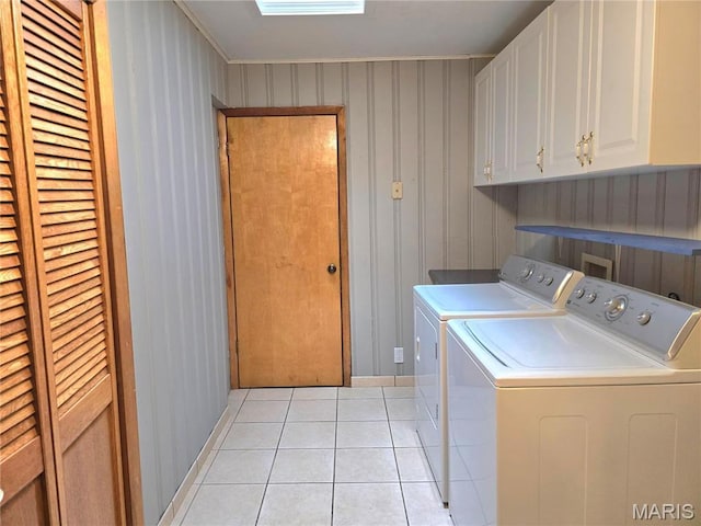 clothes washing area with cabinet space, separate washer and dryer, light tile patterned floors, and baseboards
