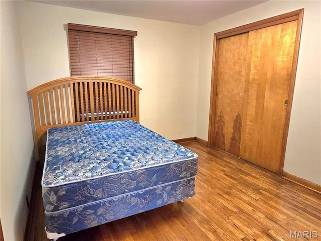 bedroom featuring hardwood / wood-style floors, baseboards, and a closet
