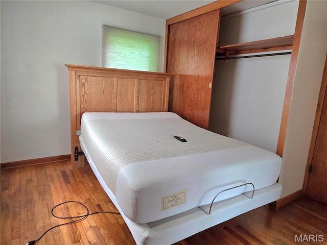 bedroom with a closet, wood finished floors, and baseboards
