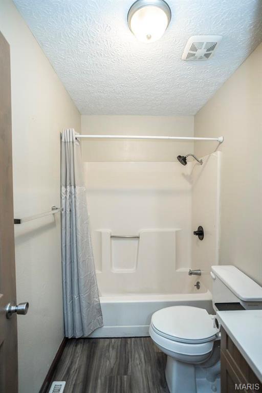 15625 Talon Ln, Saint Robert, MO 65584 - bathroom featuring wood finished floors, a textured ceiling, shower / bath combo, toilet, and vanity