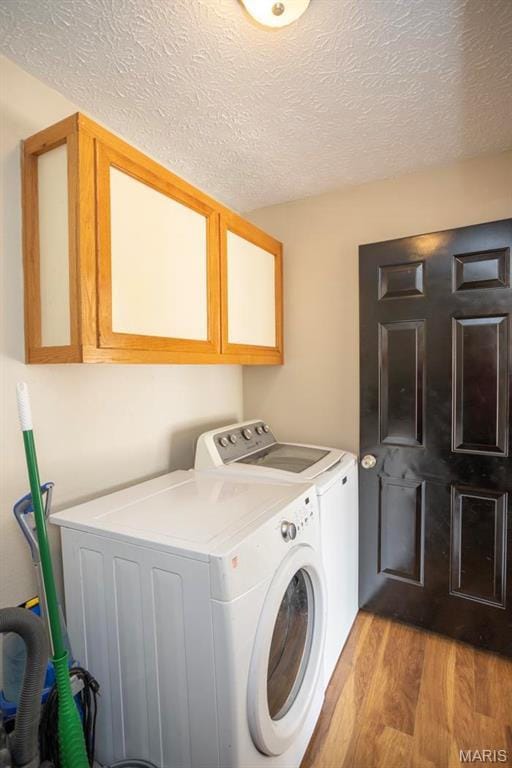 15625 Talon Ln, Saint Robert, MO 65584 - laundry room with washing machine and dryer, light wood-style floors, a textured ceiling, and cabinet space