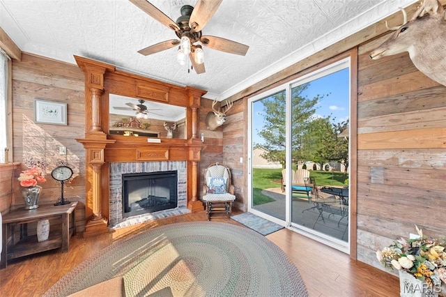 235 River Bluff Ct, Troy, MO 63379 - unfurnished living room featuring wooden walls, a ceiling fan, wood finished floors, crown molding, and a brick fireplace